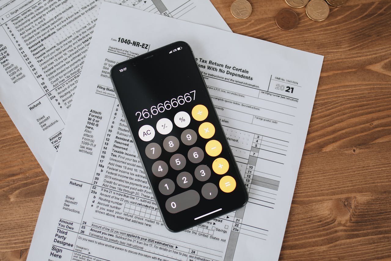 Overhead view of smartphone calculator on tax forms for finance and accounting.